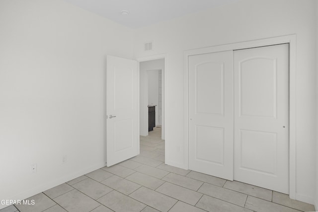 unfurnished bedroom with light tile patterned floors and a closet