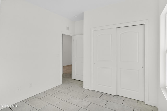 unfurnished bedroom with light tile patterned flooring and a closet