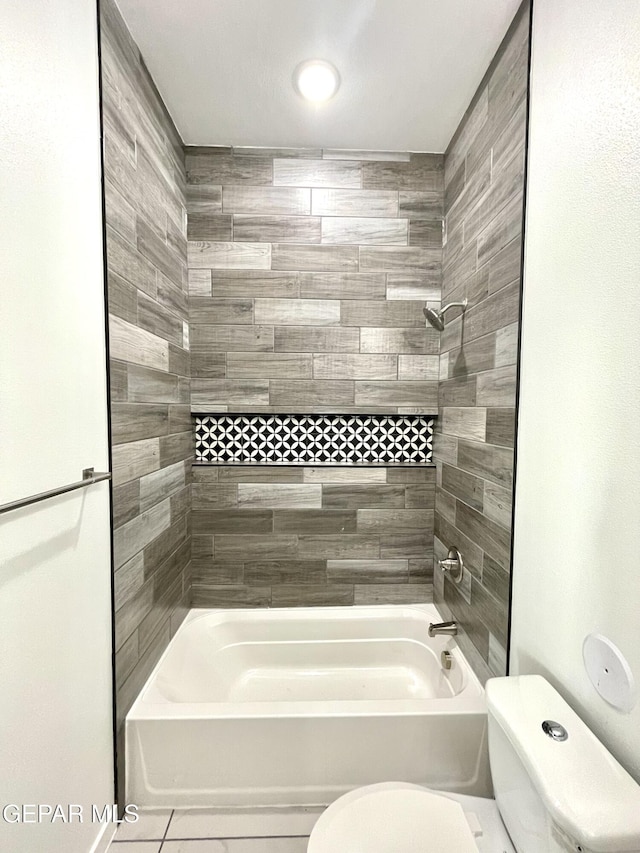 bathroom with toilet, tile patterned flooring, and tiled shower / bath combo