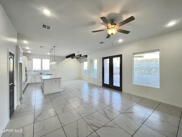 kitchen featuring ceiling fan, pendant lighting, a kitchen island, sink, and white cabinetry