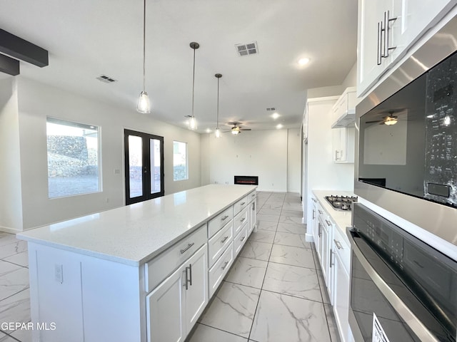 kitchen with french doors, a kitchen island, pendant lighting, and white cabinets