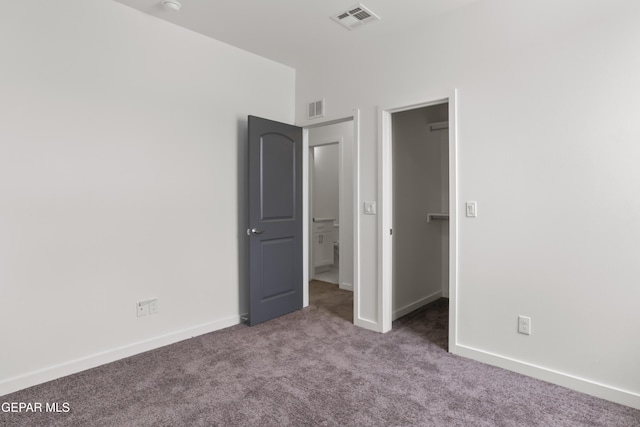 unfurnished bedroom featuring a walk in closet and carpet floors