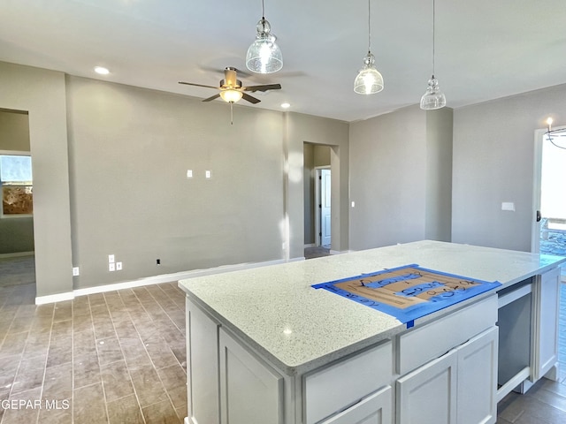 kitchen with ceiling fan, decorative light fixtures, a center island, white cabinetry, and light stone countertops