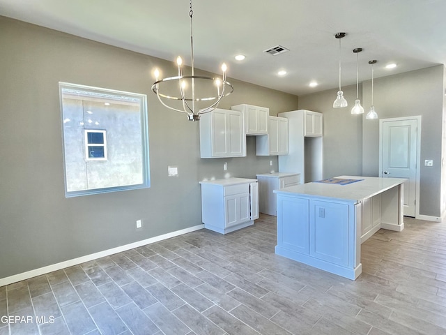 kitchen with hanging light fixtures, white cabinets, a center island, and an inviting chandelier