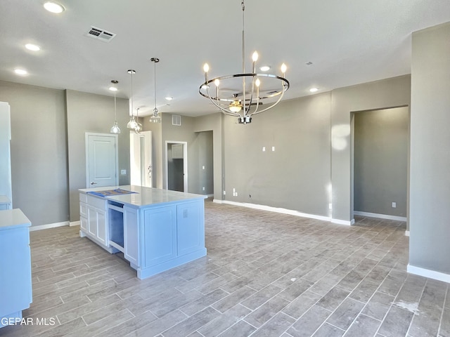 kitchen with hanging light fixtures, white cabinets, an inviting chandelier, and a center island