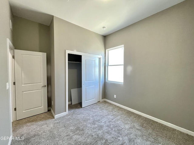 unfurnished bedroom featuring light carpet and a closet