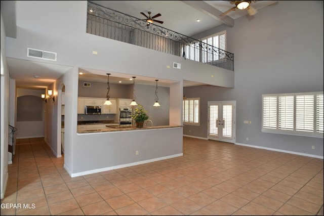 interior space with appliances with stainless steel finishes, hanging light fixtures, a high ceiling, and light tile patterned flooring