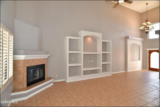 unfurnished living room featuring built in shelves, light tile patterned flooring, a towering ceiling, and a fireplace