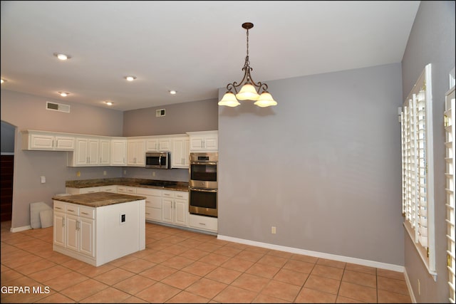 kitchen featuring light tile patterned floors, a center island, stainless steel appliances, and white cabinetry