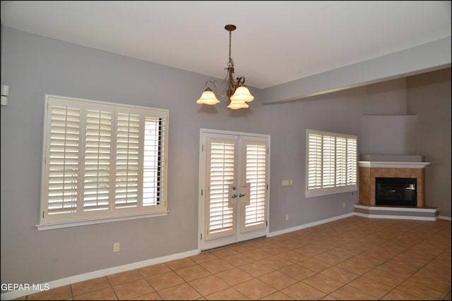 unfurnished living room featuring light tile patterned floors, a tile fireplace, and a chandelier