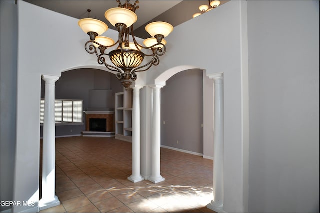 unfurnished dining area featuring tile patterned flooring, ornate columns, a fireplace, and a chandelier