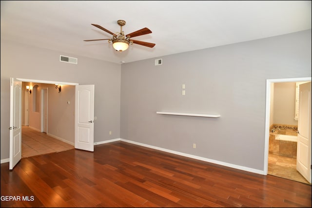 empty room with ceiling fan and dark hardwood / wood-style flooring