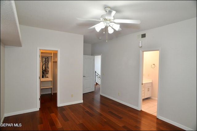 unfurnished bedroom featuring a walk in closet, ensuite bath, ceiling fan, dark hardwood / wood-style flooring, and a closet