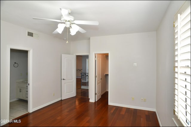 unfurnished bedroom with ensuite bathroom, ceiling fan, dark hardwood / wood-style flooring, and a walk in closet