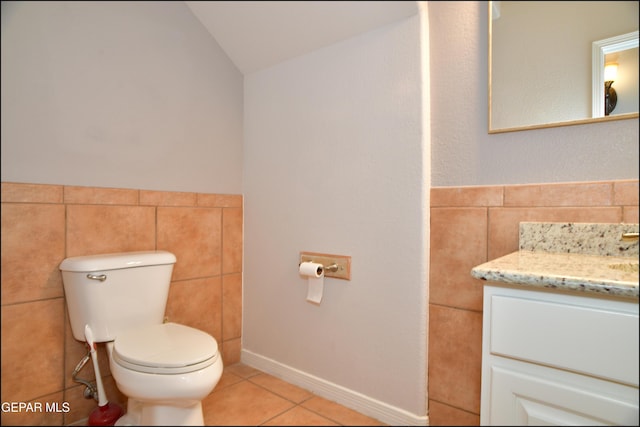 bathroom with toilet, vanity, tile patterned floors, and lofted ceiling