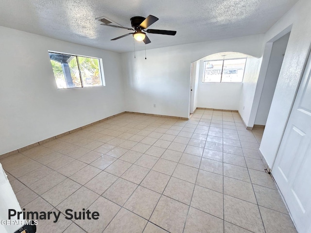 tiled empty room featuring ceiling fan and a textured ceiling