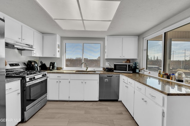 kitchen featuring dark stone counters, a textured ceiling, stainless steel appliances, sink, and white cabinets