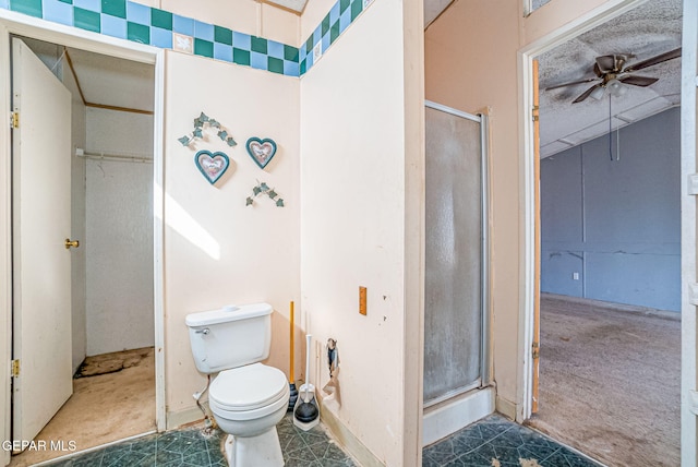 bathroom featuring ceiling fan, a shower with shower door, and toilet