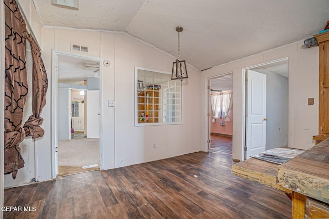 unfurnished dining area featuring a textured ceiling, dark hardwood / wood-style flooring, and vaulted ceiling