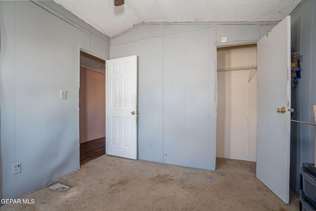 unfurnished bedroom with a textured ceiling, ceiling fan, light carpet, and vaulted ceiling