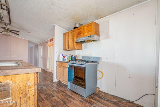 kitchen with stainless steel gas range, vaulted ceiling, ceiling fan, dark wood-type flooring, and exhaust hood