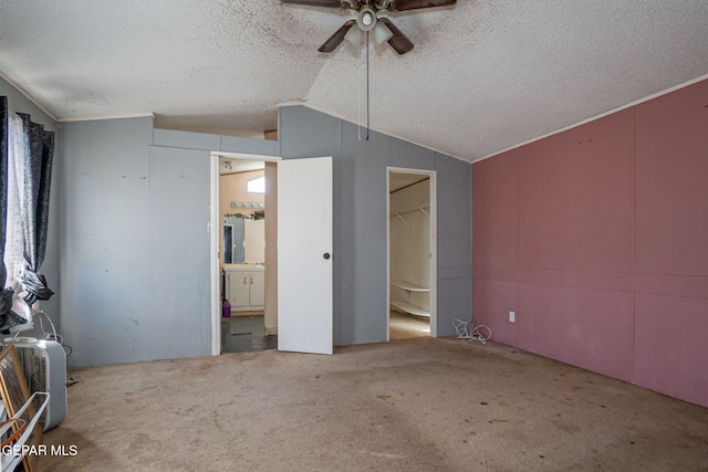 unfurnished bedroom with lofted ceiling, a walk in closet, carpet flooring, ceiling fan, and a closet