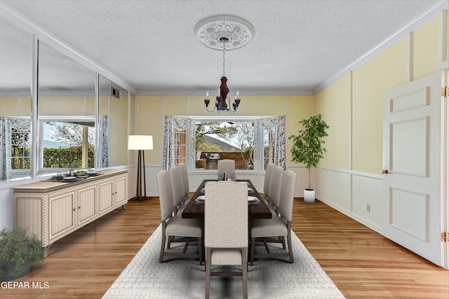 dining room with ornamental molding, light wood-type flooring, a wealth of natural light, and a notable chandelier