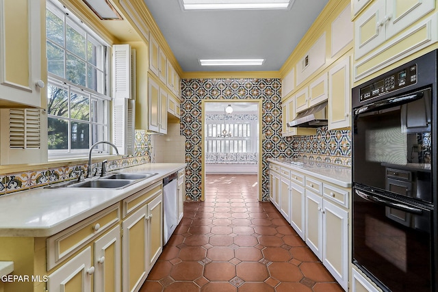 kitchen featuring sink, stainless steel dishwasher, double oven, cream cabinets, and ornamental molding