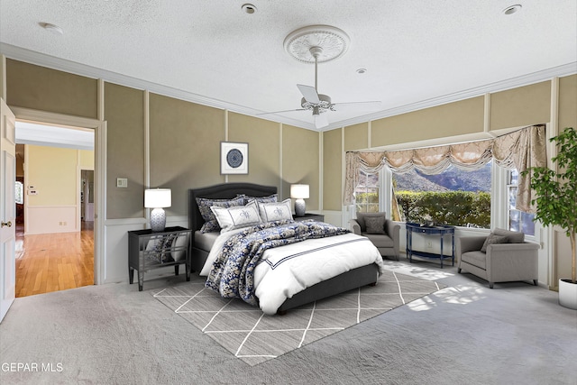 carpeted bedroom featuring ceiling fan, crown molding, and a textured ceiling