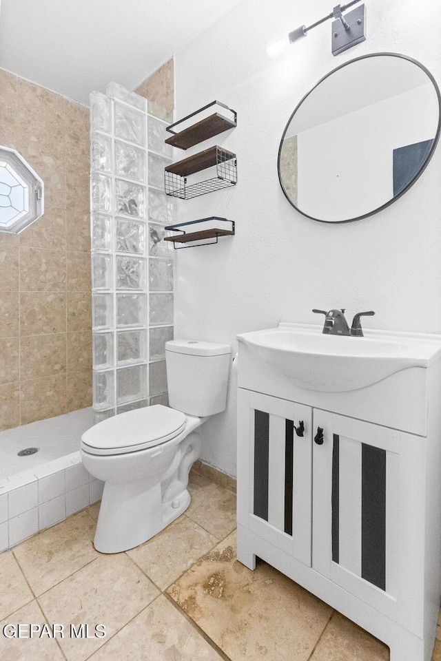 bathroom with vanity, toilet, and tiled shower