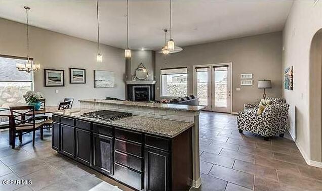 kitchen with a center island, light stone countertops, decorative light fixtures, stainless steel gas cooktop, and a chandelier