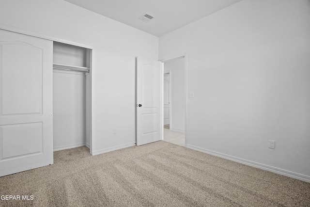 unfurnished bedroom with light colored carpet and a closet