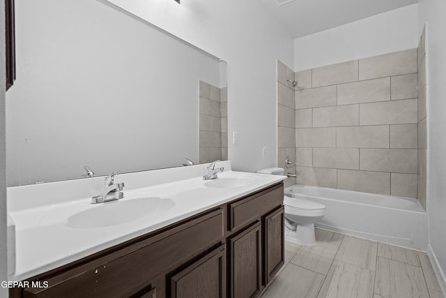 full bathroom featuring vanity, tiled shower / bath combo, and toilet