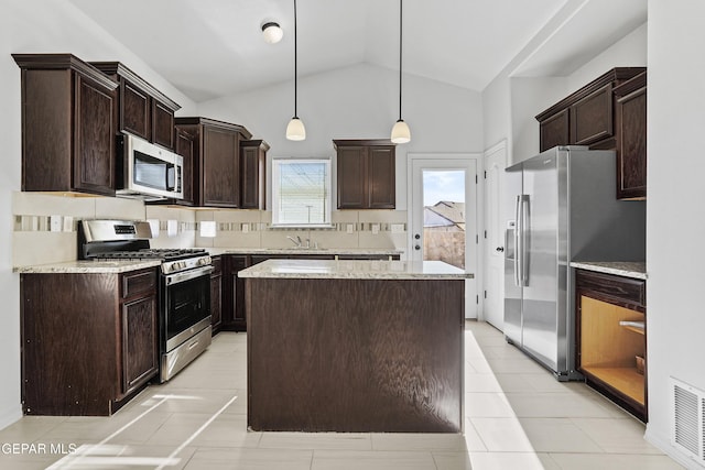 kitchen featuring a center island, lofted ceiling, appliances with stainless steel finishes, tasteful backsplash, and decorative light fixtures