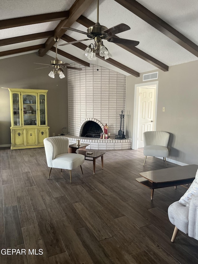 living room featuring dark hardwood / wood-style flooring, a brick fireplace, a textured ceiling, ceiling fan, and vaulted ceiling with beams