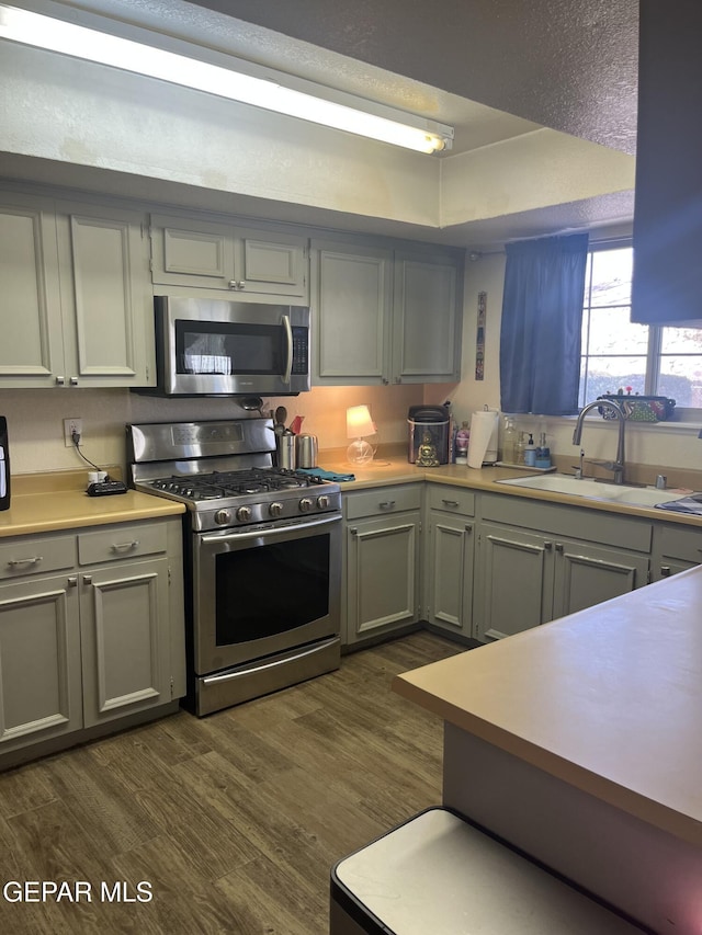 kitchen featuring gray cabinetry, sink, dark hardwood / wood-style floors, and appliances with stainless steel finishes