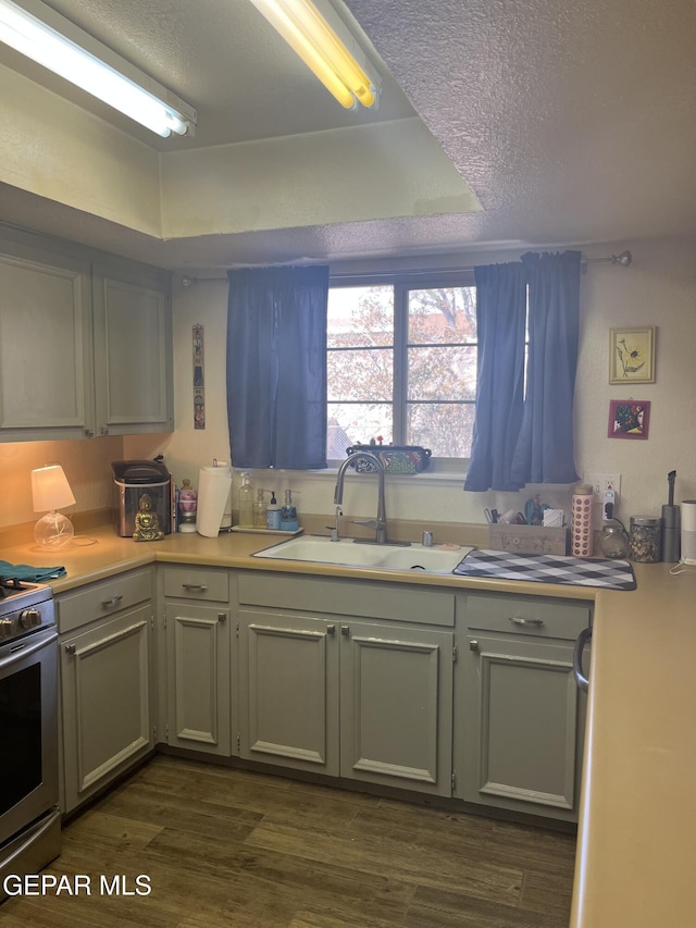 kitchen featuring a textured ceiling, dark hardwood / wood-style floors, sink, and stainless steel range