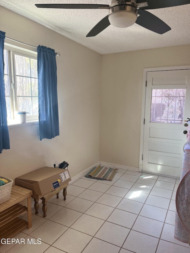 interior space featuring ceiling fan, light tile patterned flooring, and a textured ceiling