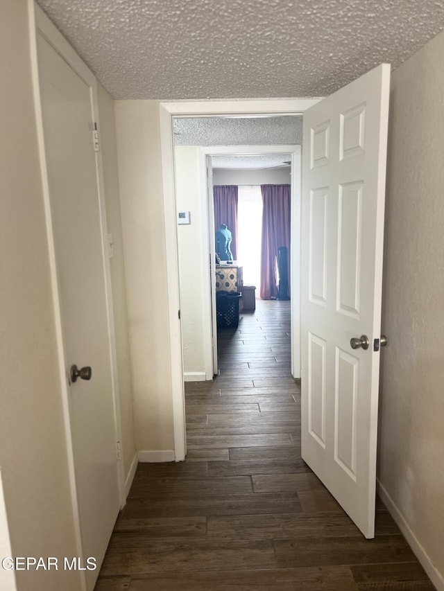 hallway with a textured ceiling and dark hardwood / wood-style floors