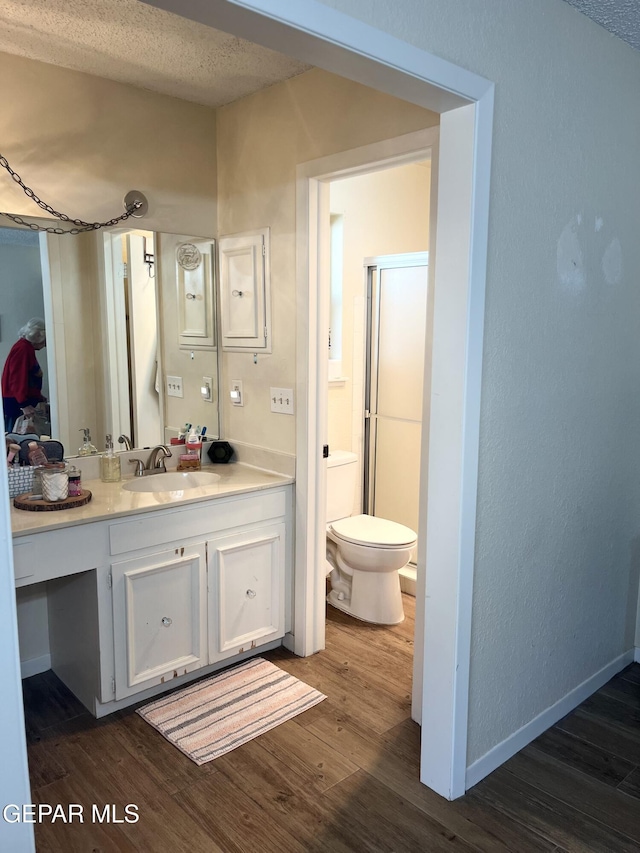 bathroom with hardwood / wood-style flooring, vanity, toilet, and an enclosed shower