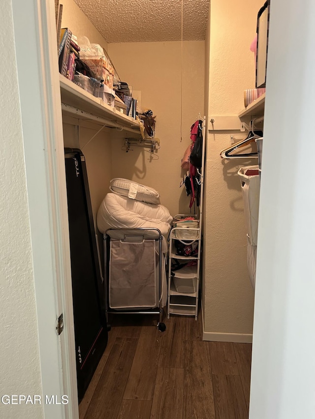 clothes washing area with a textured ceiling and dark wood-type flooring