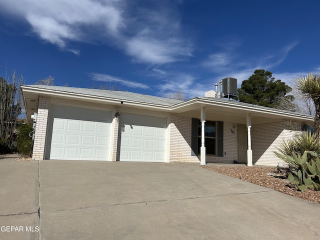 ranch-style home featuring cooling unit, covered porch, and a garage