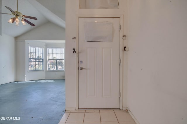 doorway with light tile patterned floors, vaulted ceiling, and ceiling fan