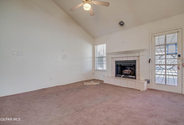 unfurnished living room with a tile fireplace, ceiling fan, carpet, and high vaulted ceiling