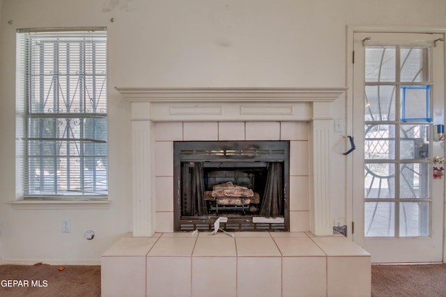 interior details featuring a tile fireplace and carpet