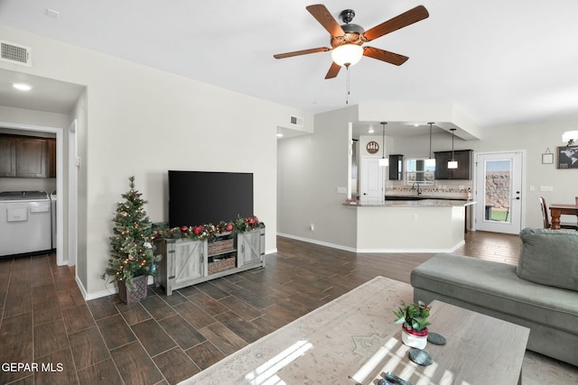 living room with ceiling fan, washer / dryer, and sink