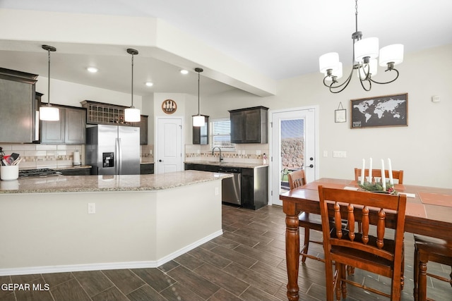 kitchen featuring dark brown cabinetry, light stone countertops, a notable chandelier, decorative light fixtures, and appliances with stainless steel finishes