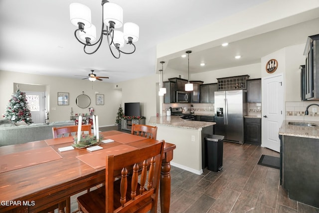 dining room with ceiling fan with notable chandelier and sink