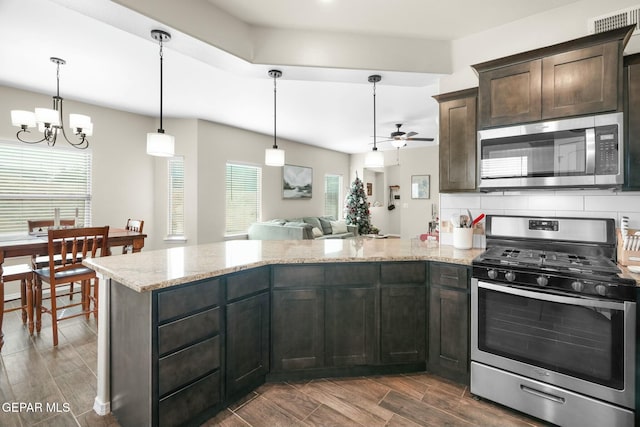 kitchen featuring pendant lighting, light stone countertops, dark brown cabinetry, and appliances with stainless steel finishes