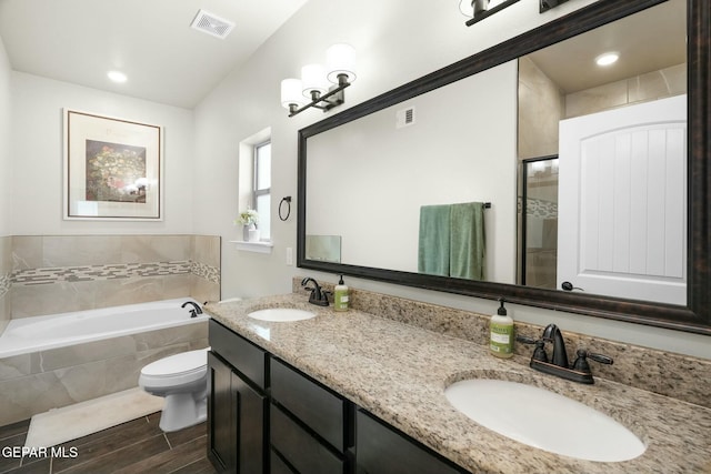 bathroom with vanity, toilet, and tiled bath